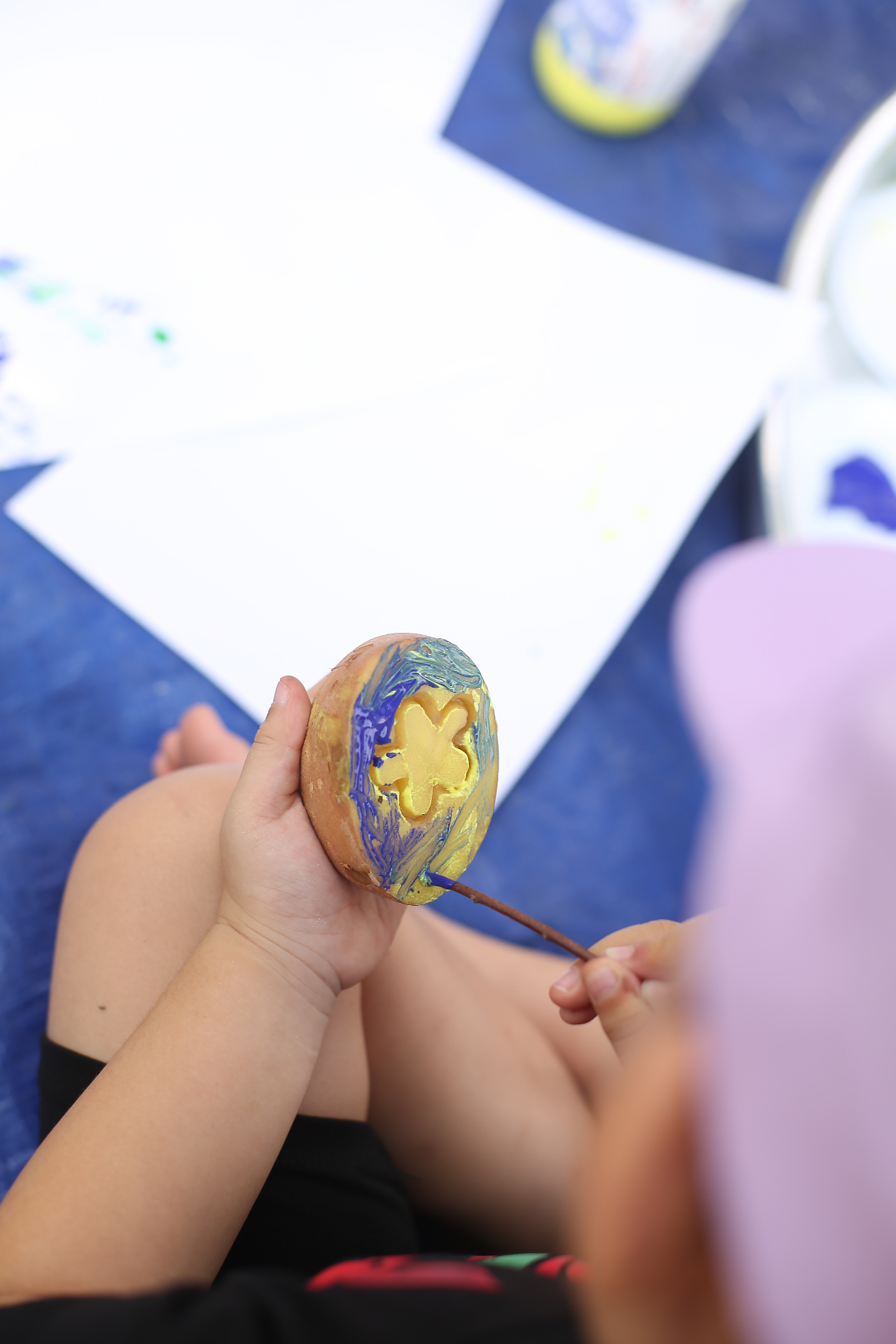 Tay bé cầm tác phẩm thủ công vẽ tay xanh-vàng vừa hoàn thành sau buổi messy play